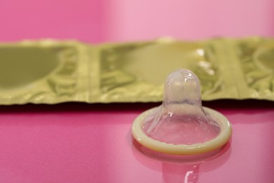 Photo of Unpacked condom and packages on pink background, closeup. Safe sex