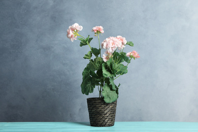 Photo of Artificial geranium plant in flower pot on light blue wooden table
