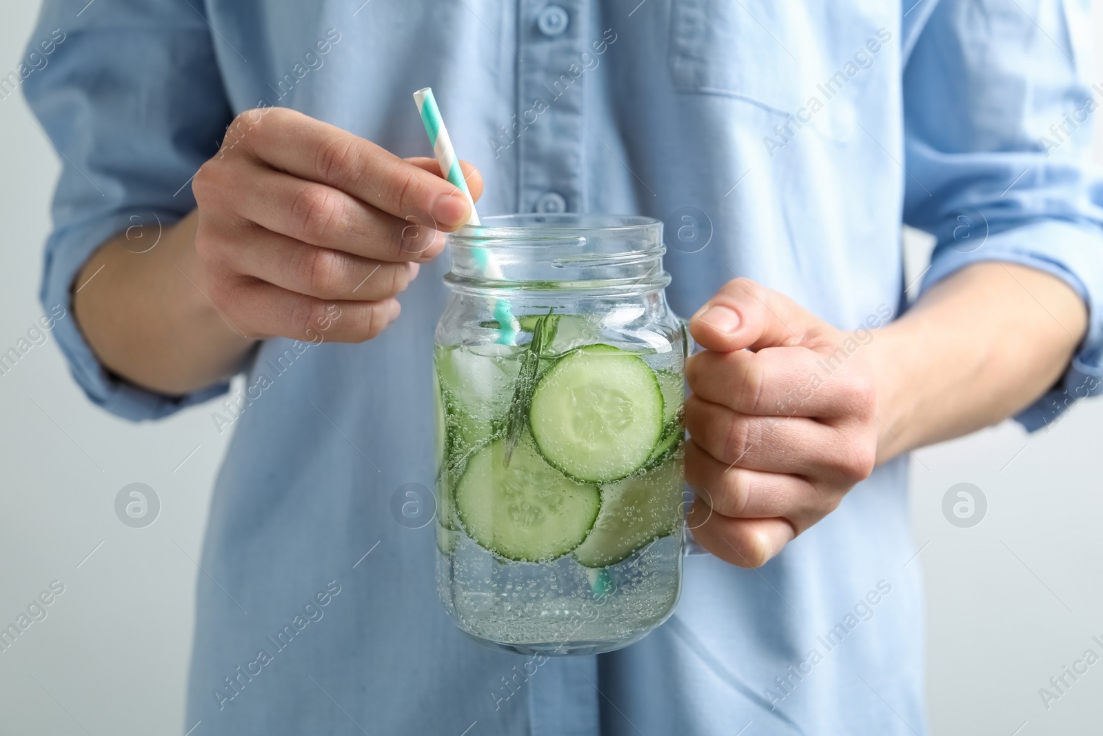 Photo of Young woman holding jar with fresh cucumber water, closeup