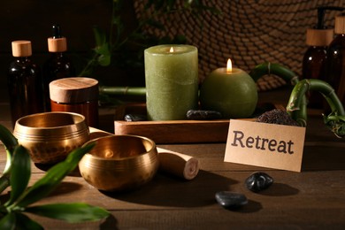 Photo of Card with word Retreat, singing bowls and burning candles on wooden table