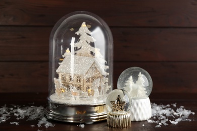 Different beautiful snow globes on wooden table