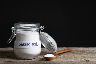 Photo of Baking soda in jar and spoon on wooden table. Space for text