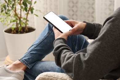 Photo of Man using smartphone with blank screen indoors, closeup. Mockup for design