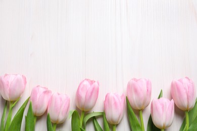 Beautiful pink spring tulips on white wooden background, flat lay. Space for text