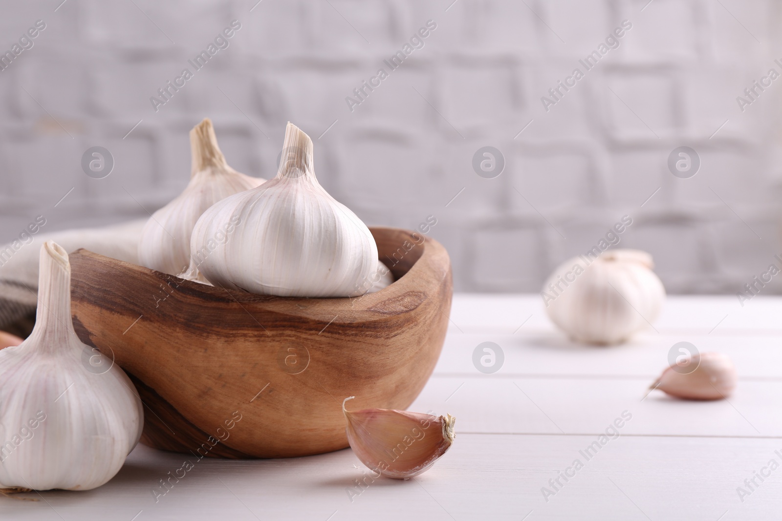 Photo of Fresh garlic on white wooden table, closeup. Space for text
