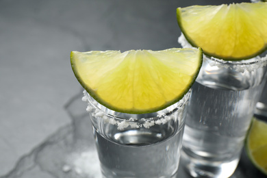 Mexican Tequila shots, lime slices and salt on table, closeup