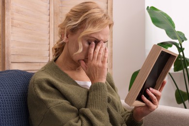 Photo of Upset middle aged woman with photo frame at home. Loneliness concept