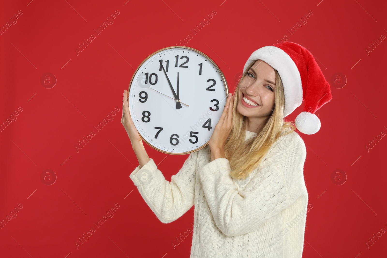 Photo of Woman in Santa hat with clock on red background. New Year countdown