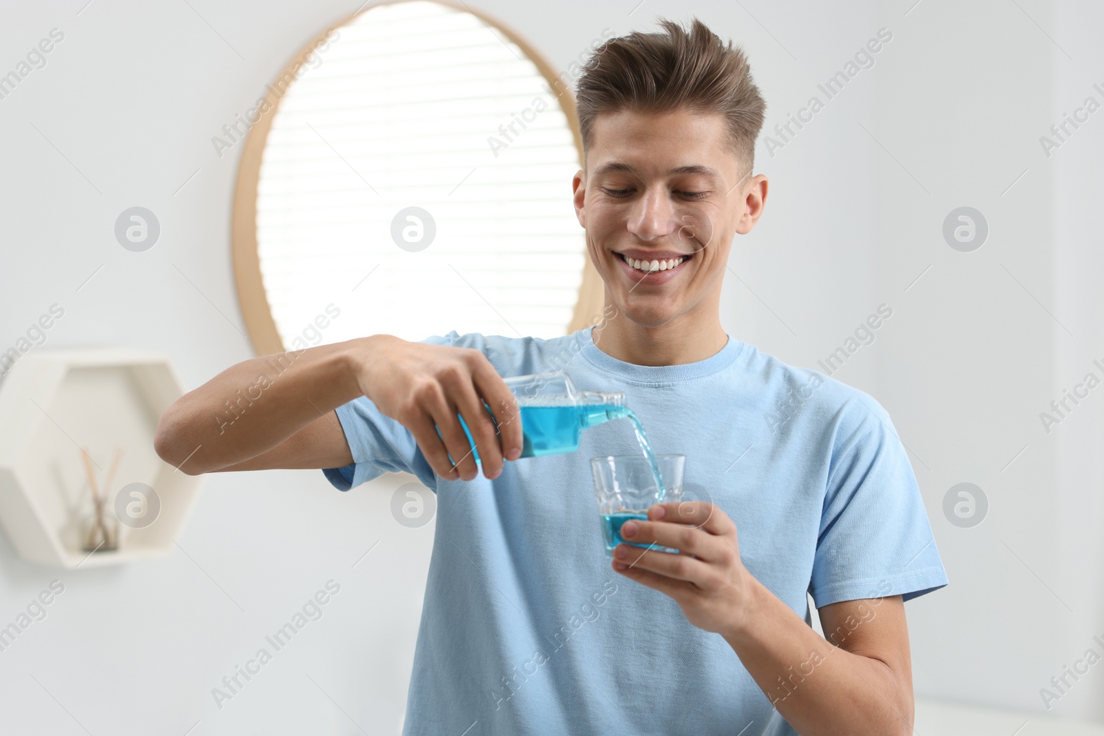 Photo of Young man using mouthwash in bathroom. Oral hygiene