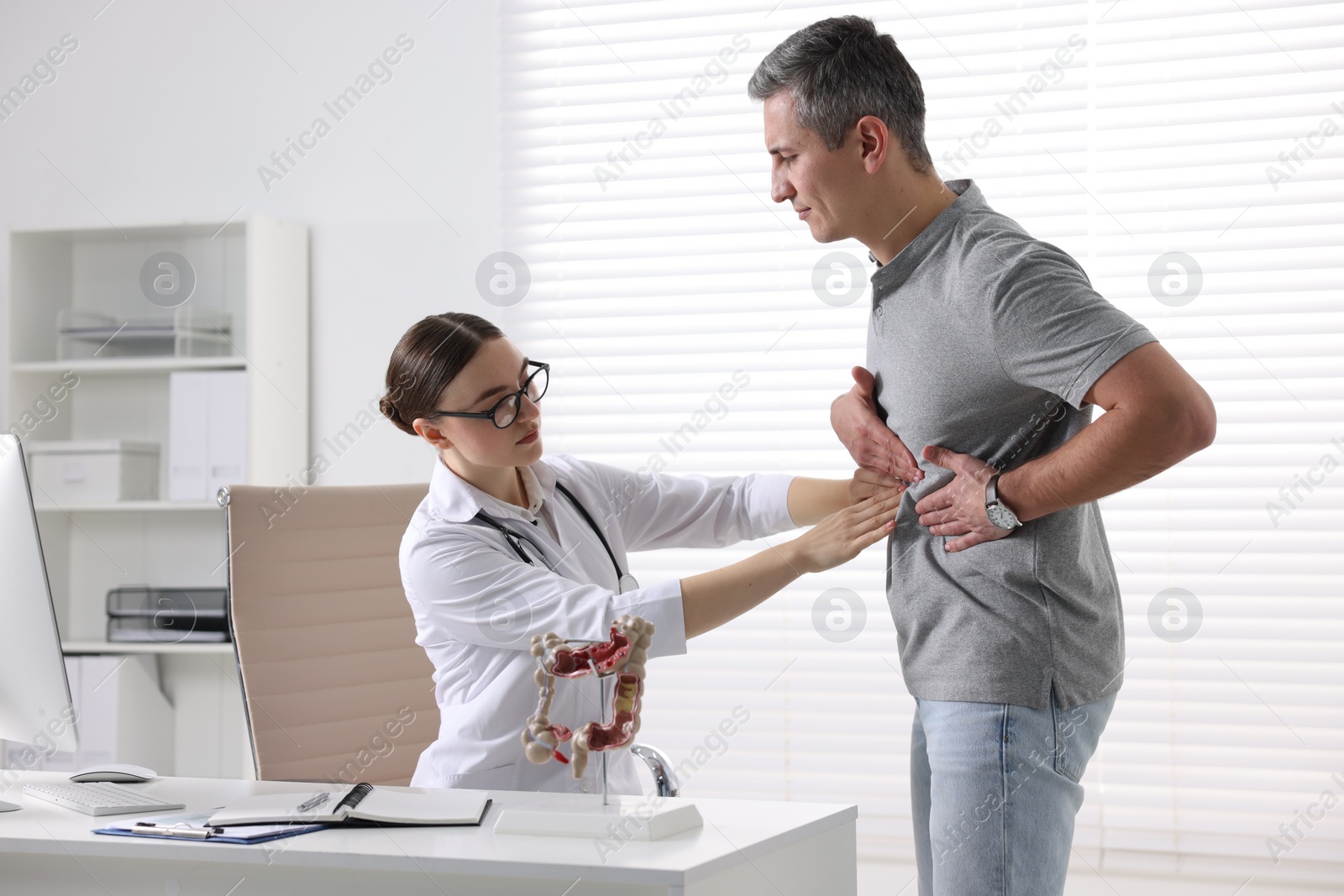 Photo of Gastroenterologist examining patient with stomach pain in clinic