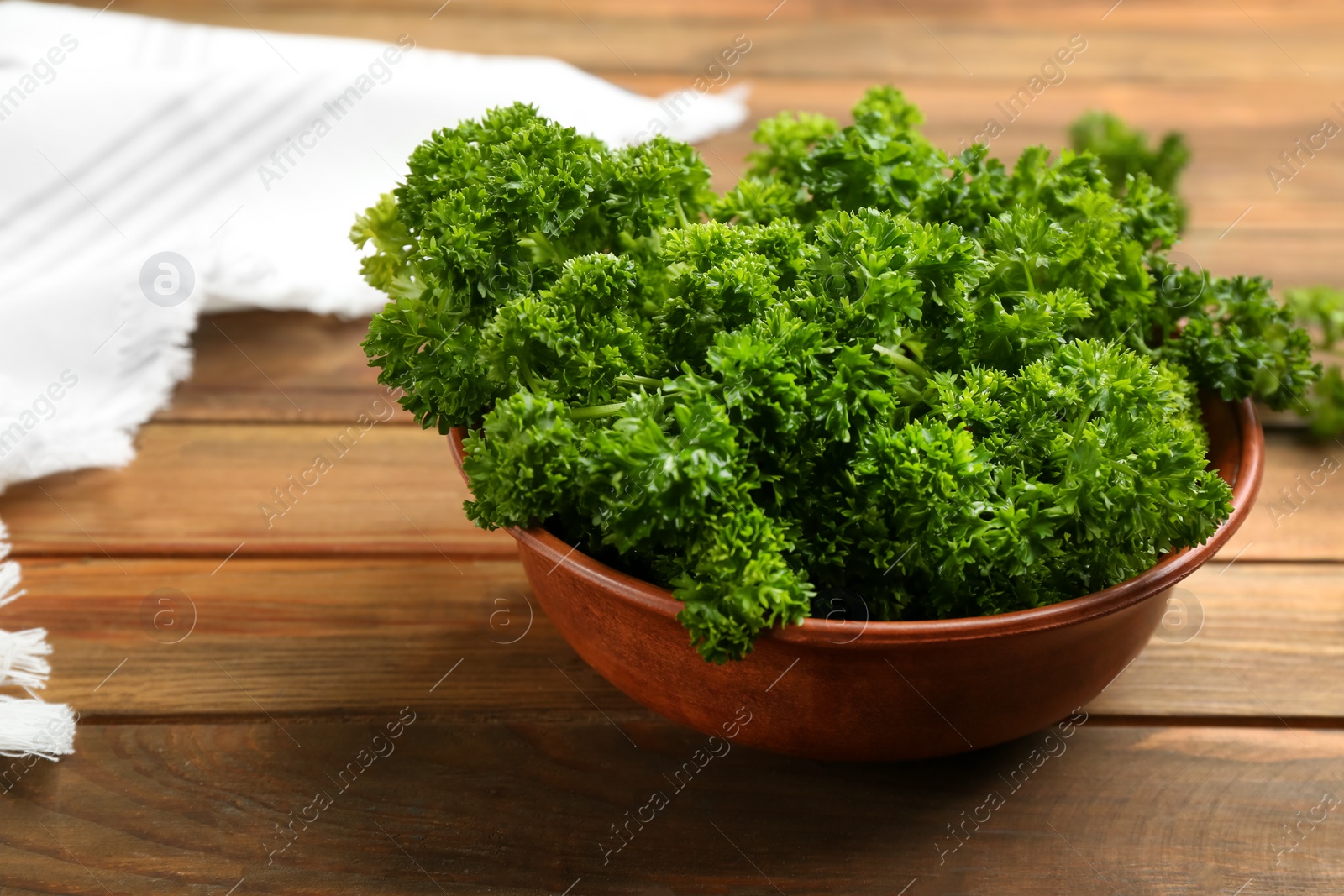 Photo of Fresh curly parsley in bowl on wooden table