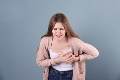 Photo of Young woman having heart attack on color background