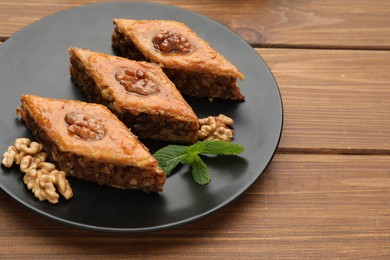 Photo of Delicious honey baklava with walnuts on wooden table, closeup