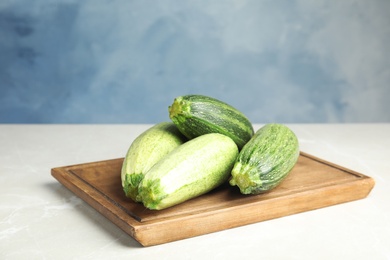 Photo of Fresh ripe green zucchinis on light table against blue background, space for text