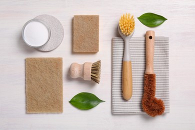 Photo of Cleaning brushes, sponges, towel, baking soda and leaves on light wooden table, flat lay