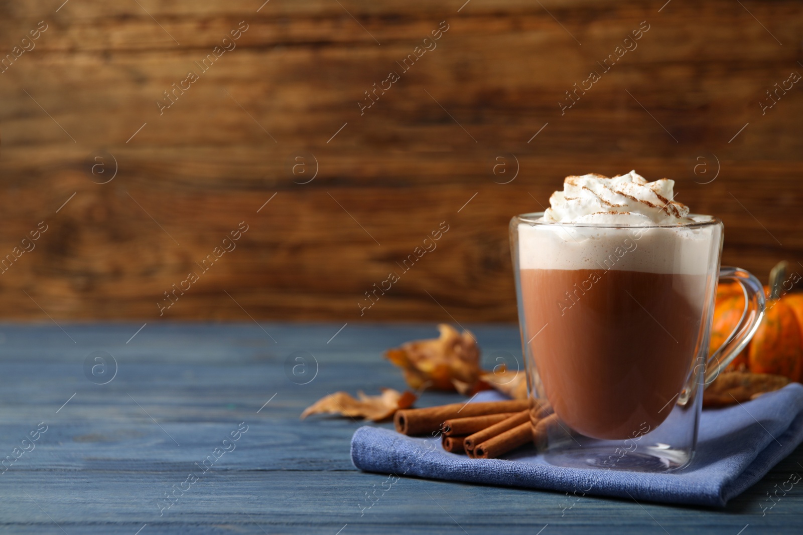 Photo of Delicious pumpkin latte on blue wooden table. Space for text