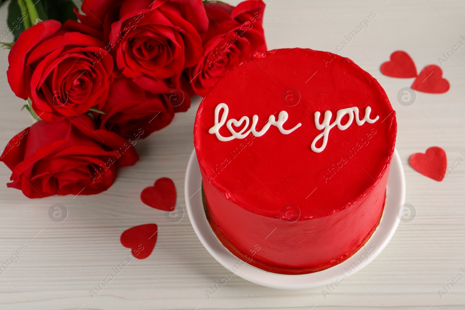 Photo of Bento cake with text Love You, roses and paper hearts on white wooden table. St. Valentine's day surprise