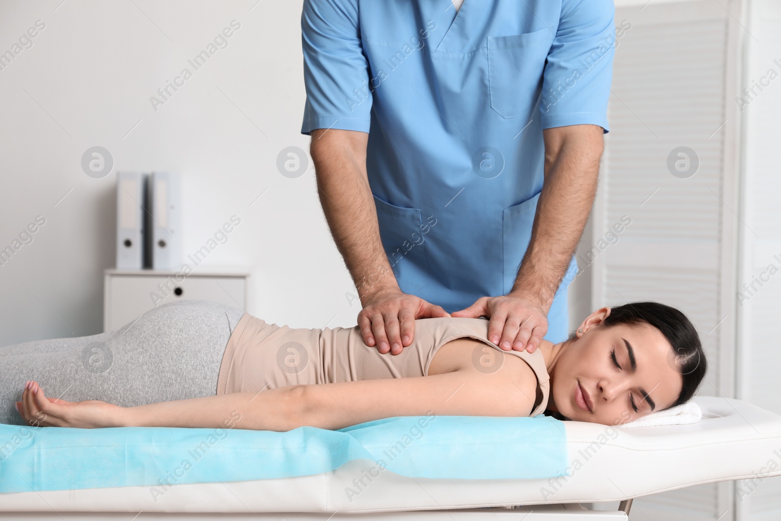 Photo of Orthopedist massaging young woman's back in clinic, closeup. Scoliosis treatment