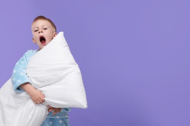 Sleepy boy with pillow yawning on purple background, space for text. Insomnia problem