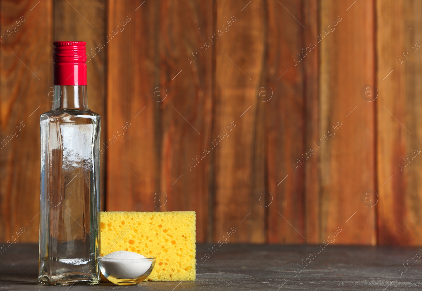 Photo of Vinegar, baking soda and sponge for cleaning on table. Space for text