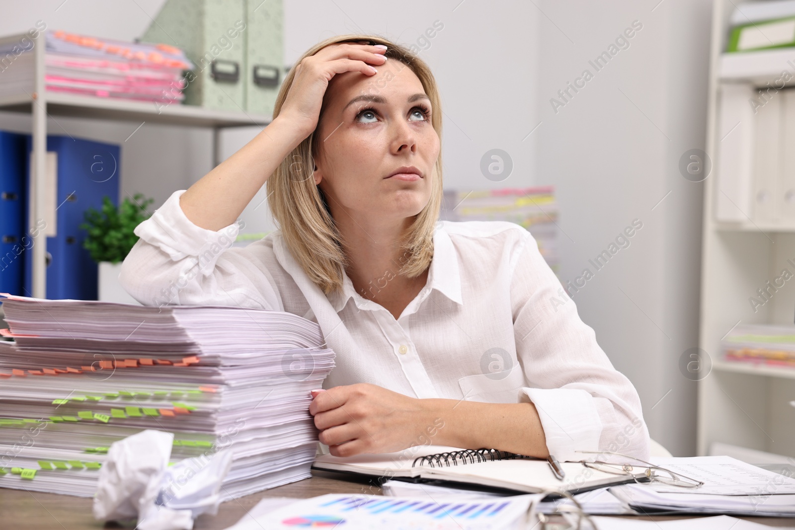 Photo of Overwhelmed woman at table with many documents in office