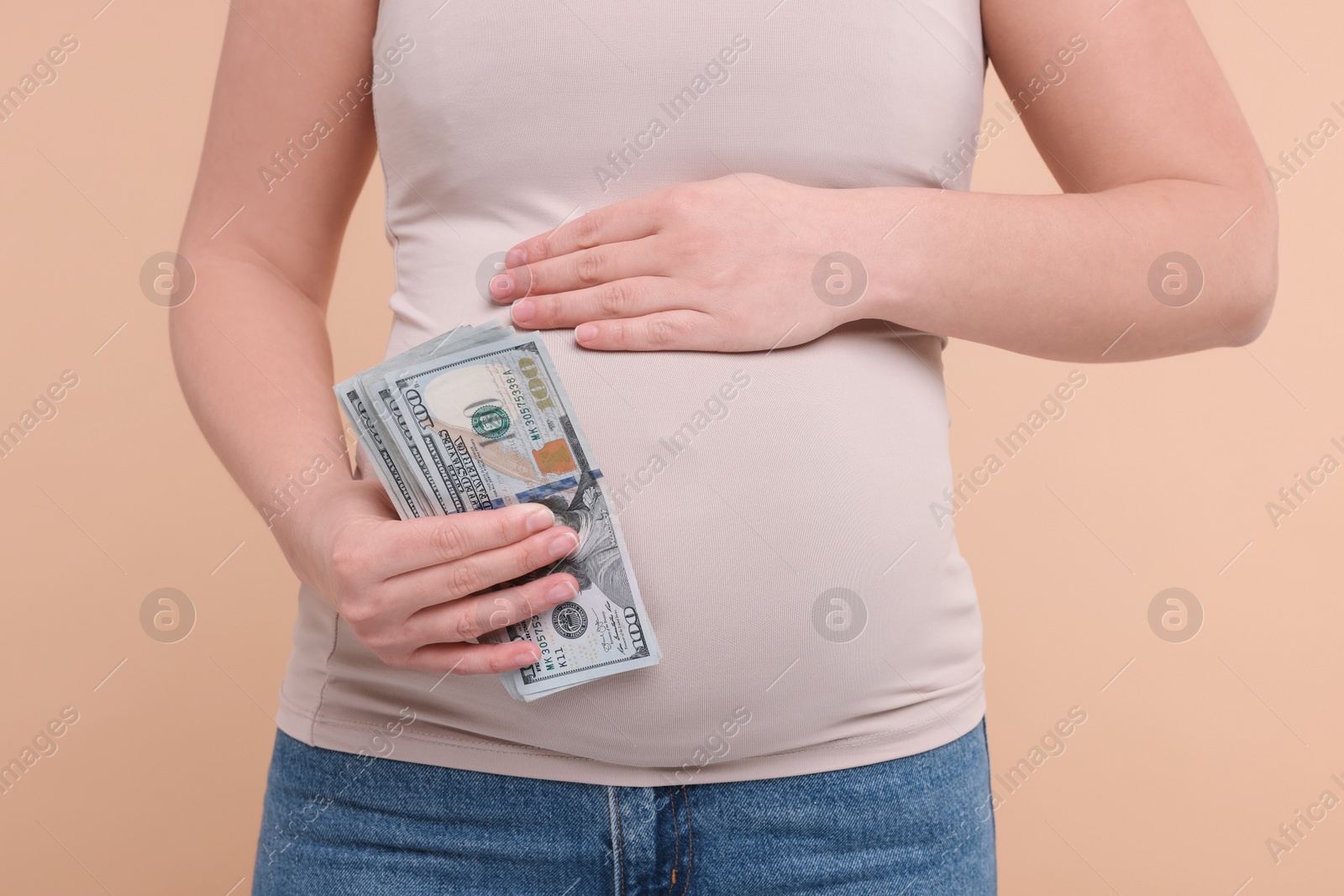 Photo of Surrogate mother. Pregnant woman with dollar banknotes on beige background, closeup