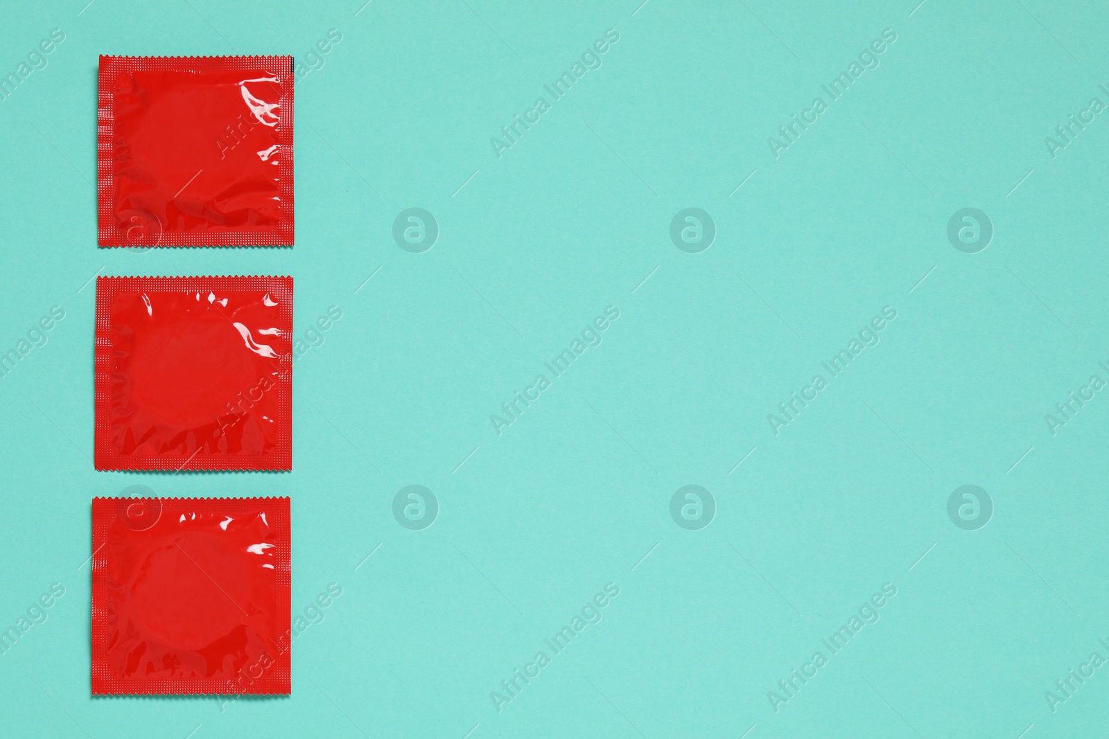 Photo of Condom packages on turquoise background, flat lay and space for text. Safe sex