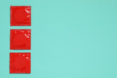 Condom packages on turquoise background, flat lay and space for text. Safe sex