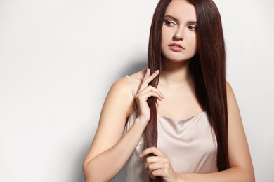 Portrait of beautiful young woman with healthy strong hair on light gray background, space for text