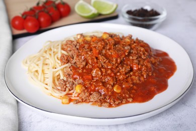 Tasty dish with fried minced meat, spaghetti, carrot and corn served on white textured table, closeup