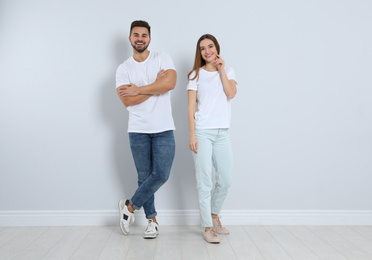 Photo of Young couple in stylish jeans near light wall