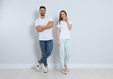 Young couple in stylish jeans near light wall