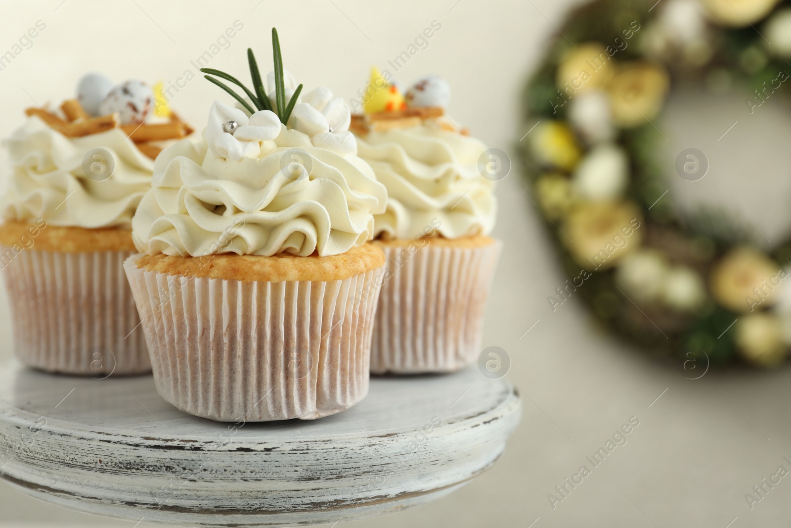 Photo of Tasty Easter cupcakes with vanilla cream on dessert stand, closeup