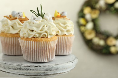 Photo of Tasty Easter cupcakes with vanilla cream on dessert stand, closeup