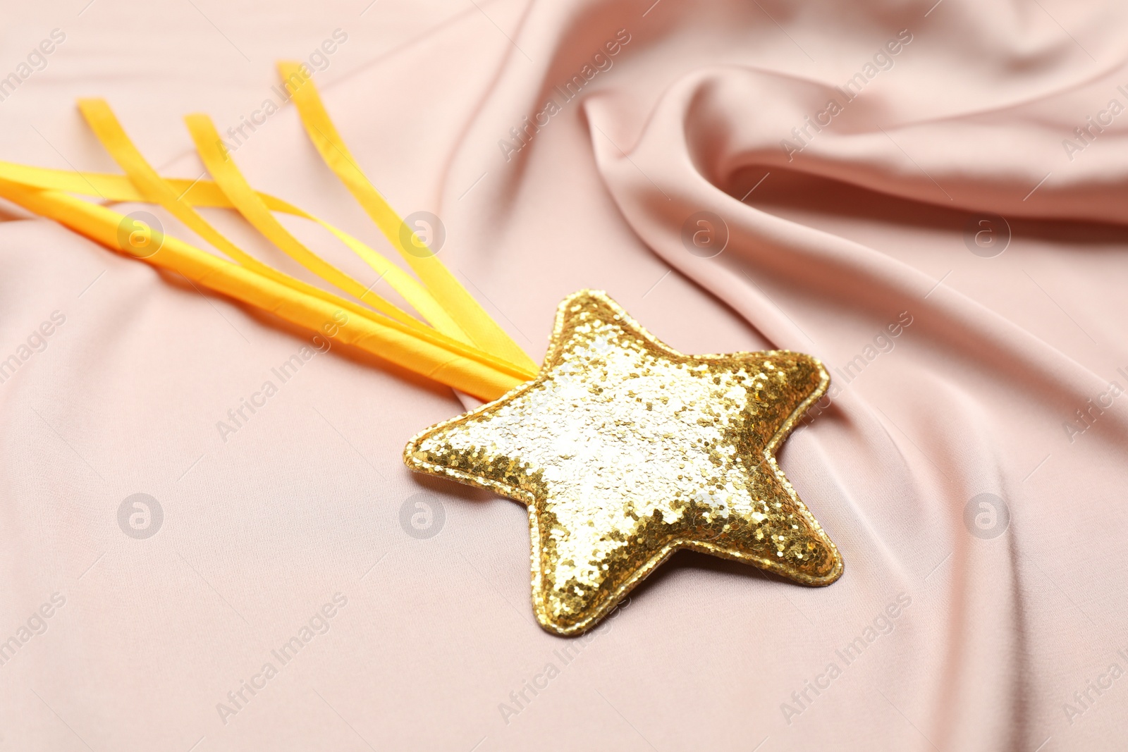 Photo of Beautiful golden magic wand on pink fabric