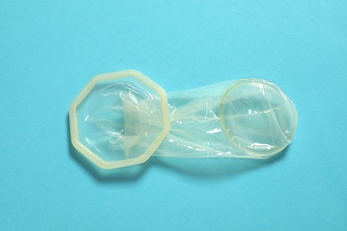 Photo of Unrolled female condom on light blue background, top view. Safe sex