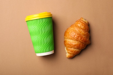 Photo of Paper coffee cup and croissant on color background, flat lay