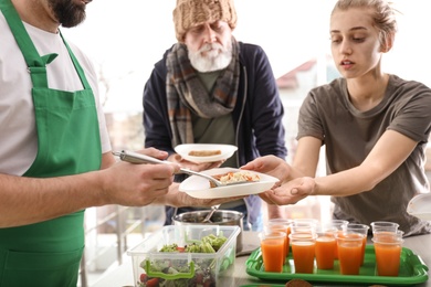 Volunteer giving food to poor people indoors