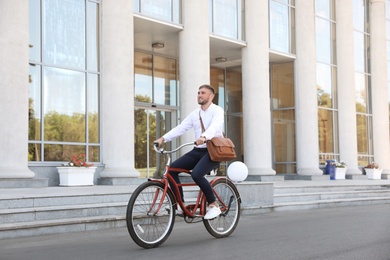 Photo of Attractive man riding bike on city street