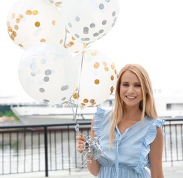 Photo of Beautiful young woman with bunch of balloons outdoors