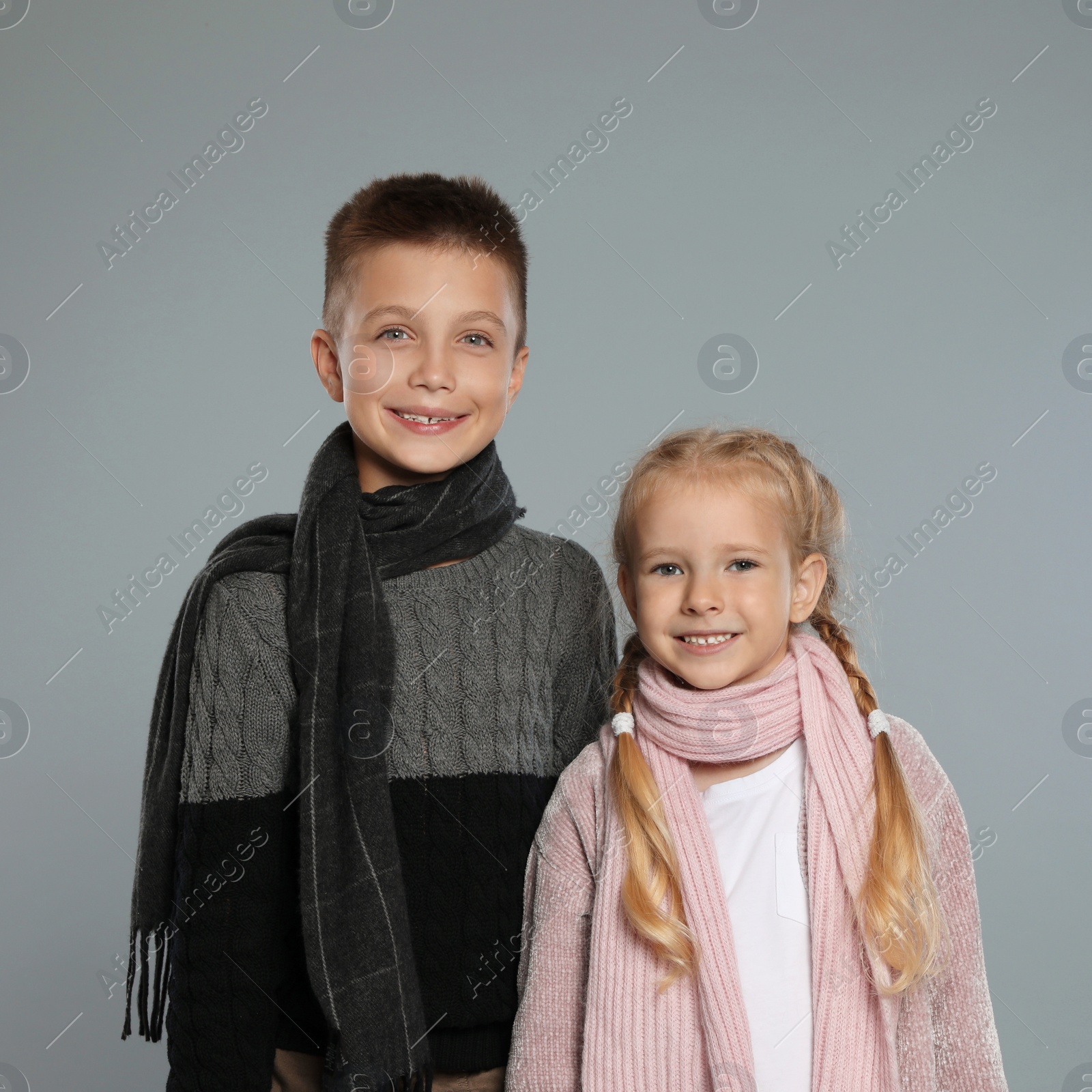 Photo of Cute little children in warm clothes on grey background. Winter season