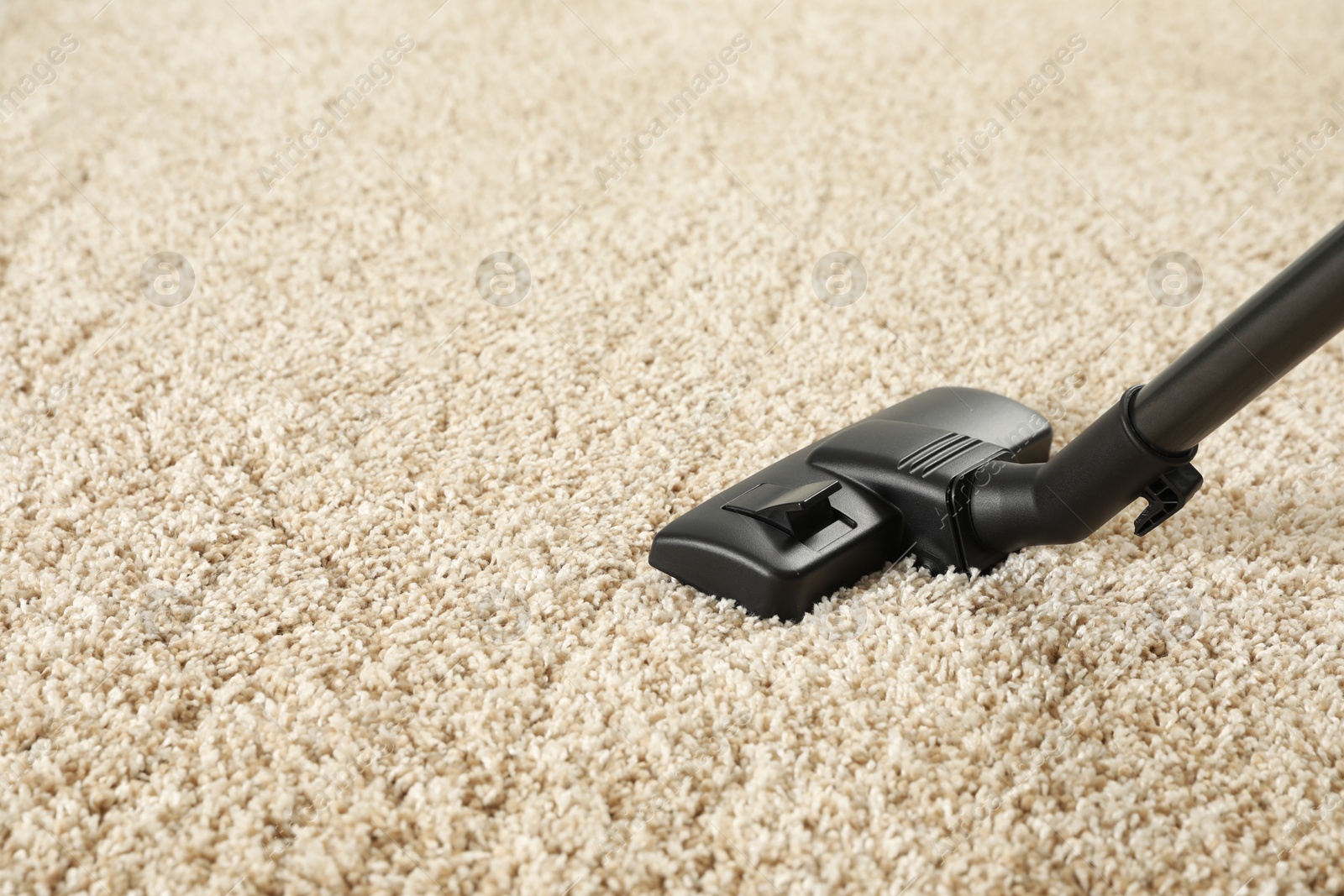 Photo of Removing dirt from beige carpet with modern vacuum cleaner. Space for text