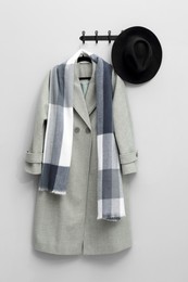 Photo of Hanger with coat, scarf and hat on light grey wall