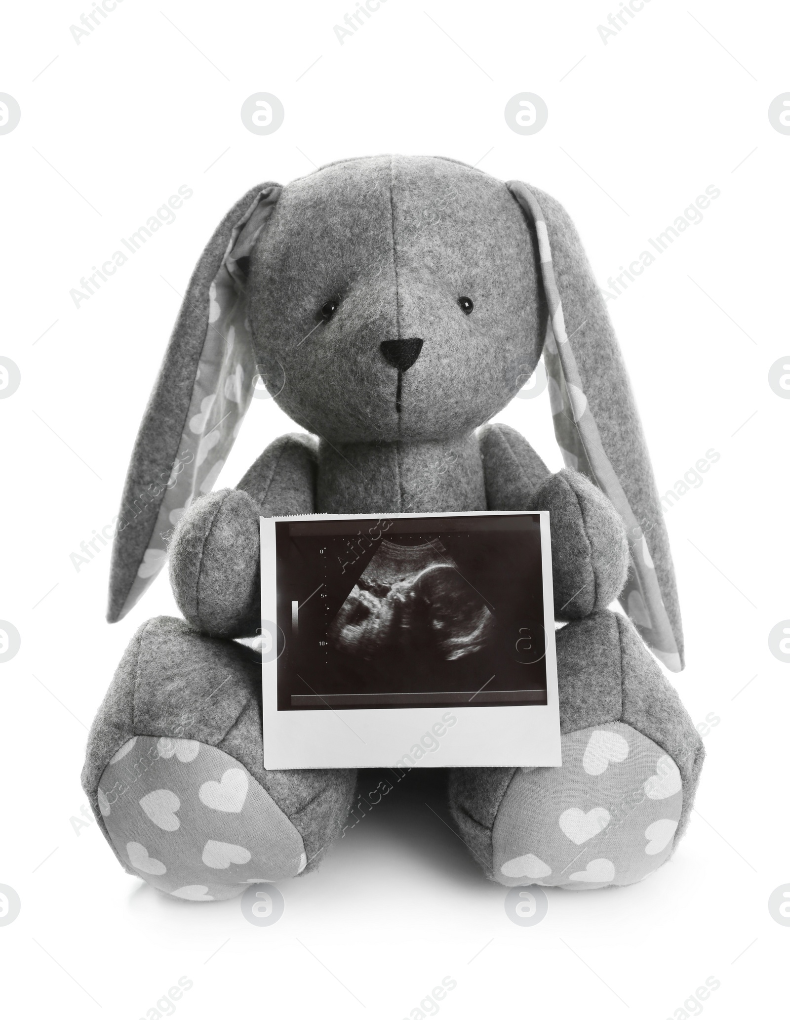 Photo of Ultrasound photo of baby and toy rabbit on white background. Concept of pregnancy