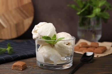 Photo of Scoopsice cream with mint leaves and caramel candies on wooden table, closeup