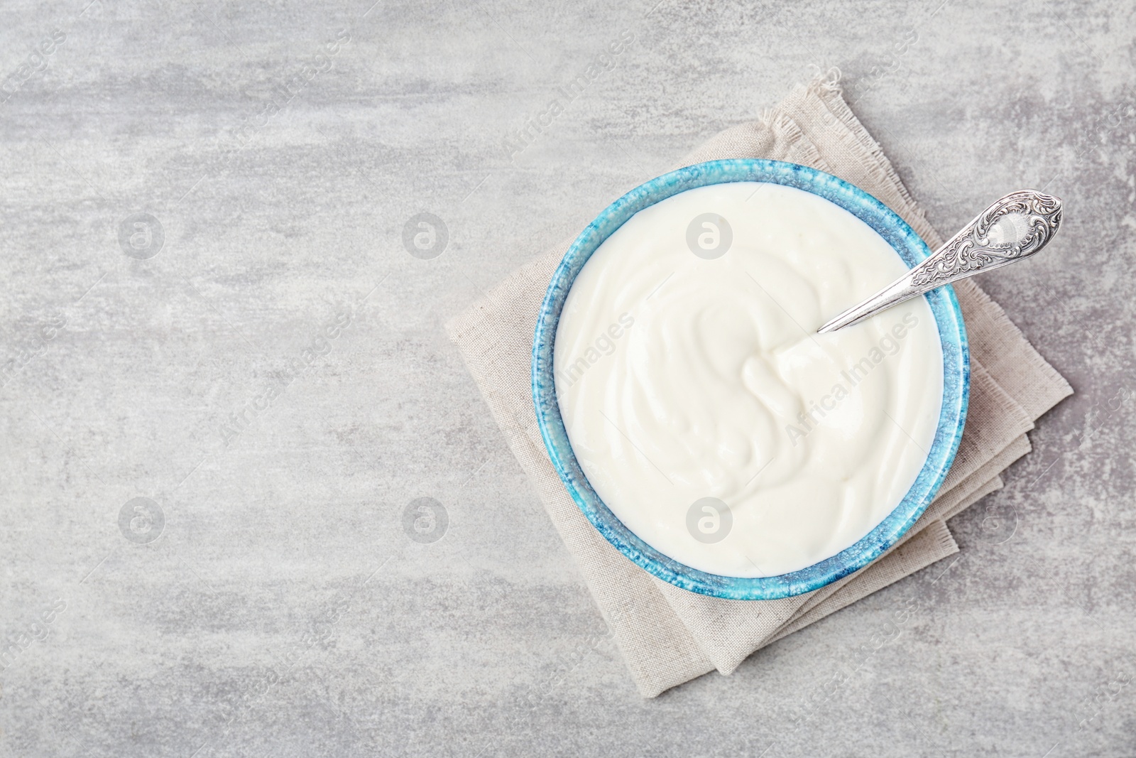 Photo of Bowl with tasty yogurt on grey background, top view