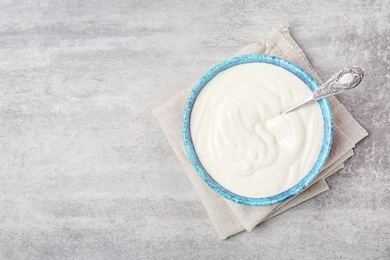 Bowl with tasty yogurt on grey background, top view