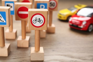 Photo of Many different miniature road signs on wooden table, space for text. Driving school