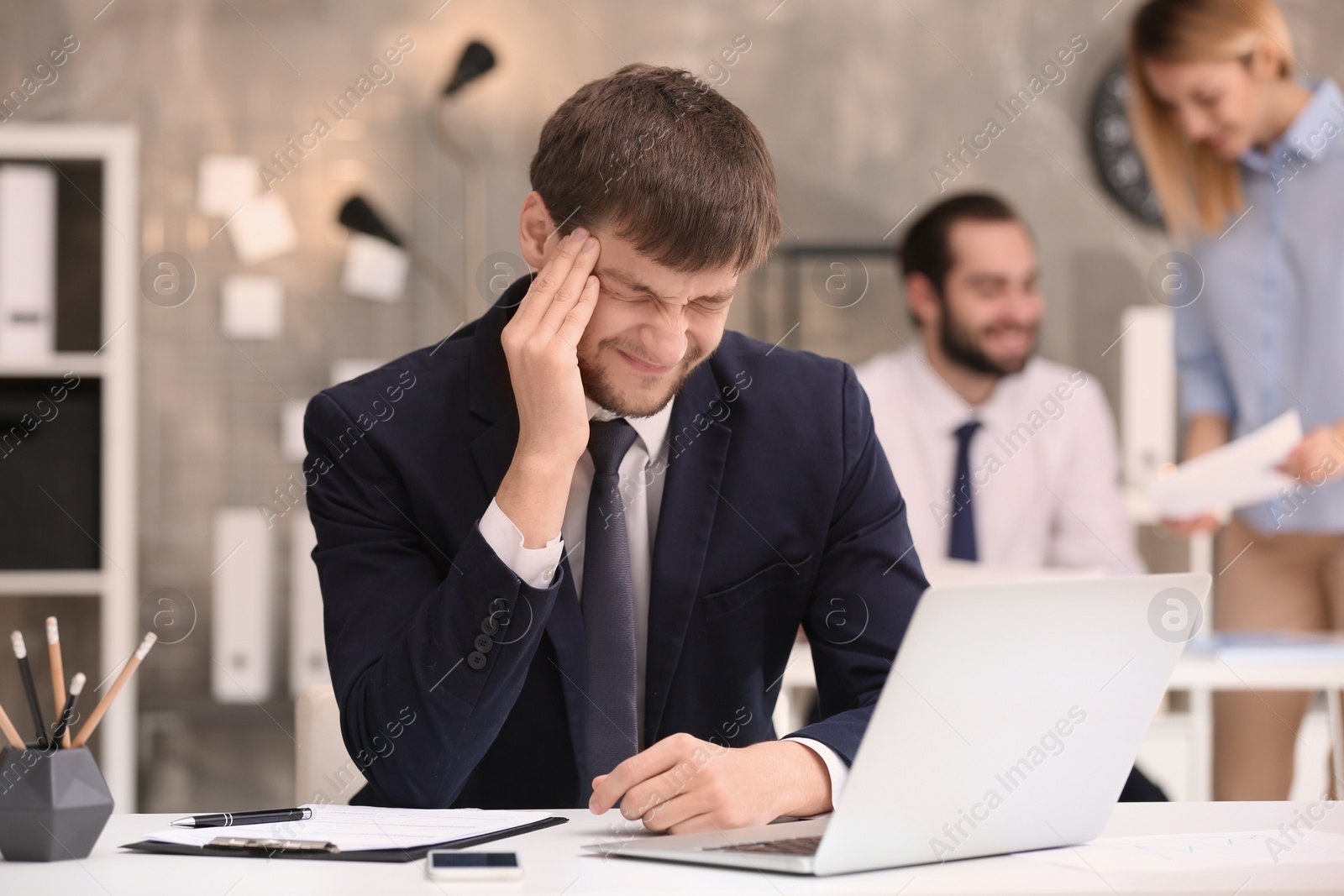 Photo of Young man suffering from headache in office