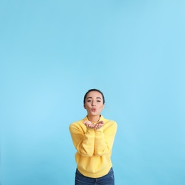 Photo of Beautiful young woman wearing yellow warm sweater on light blue background. Space for text